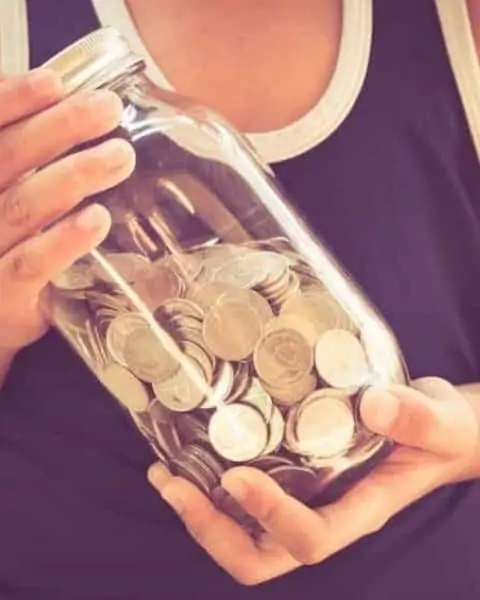 A woman holding a jar of quarters.