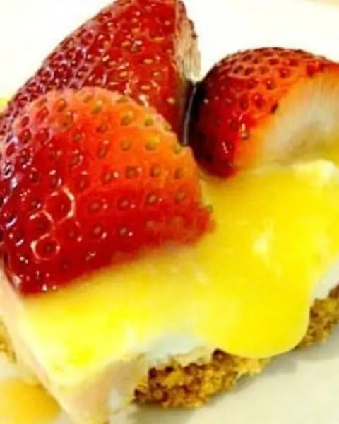 Lemon berry cheesecake bars with strawberries on top.