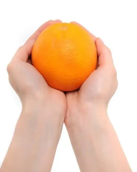 A child holding an orange in the palm of their hands.