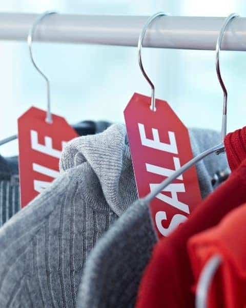 Shirts and sweaters with red sale signs.