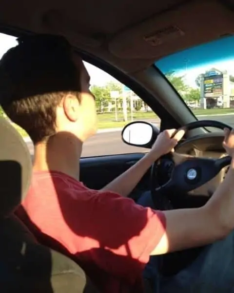 A young man driving with both hands on the steering wheel.