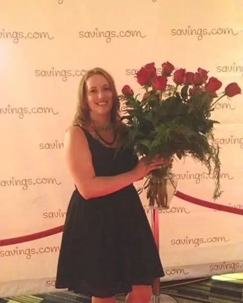 A smiling woman holding a beautiful bouquet of red roses.