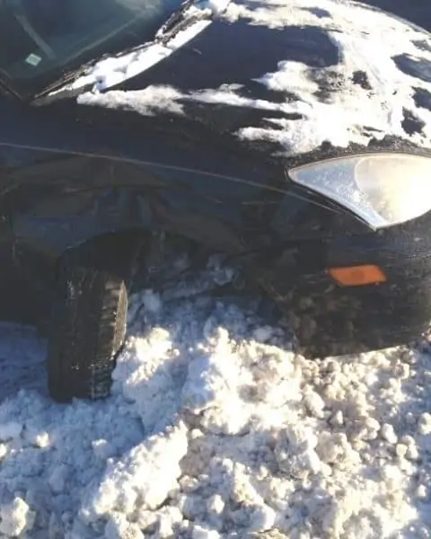 A car with the front tire turned sideways from the snow.
