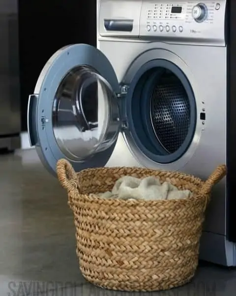 Washing machine with a full wicker basket in front of the machine.