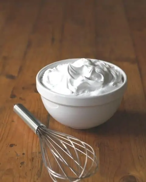 Bowl of whipped cream with whisk.