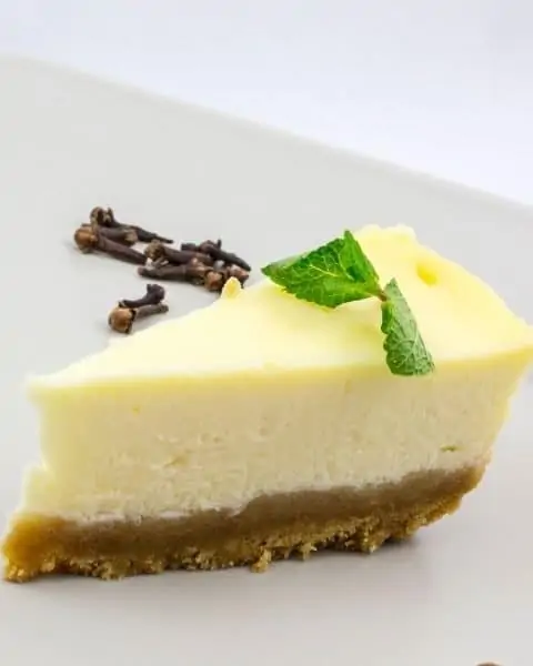 A slice of white chocolate cheesecake recipe with a small green mint on top.