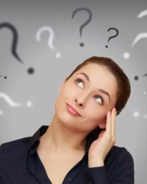 A woman tilting her head in question with question marks above her head.