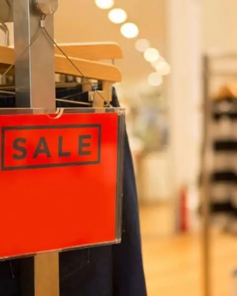 A red sale sign on a clothes wrack at the department store.
