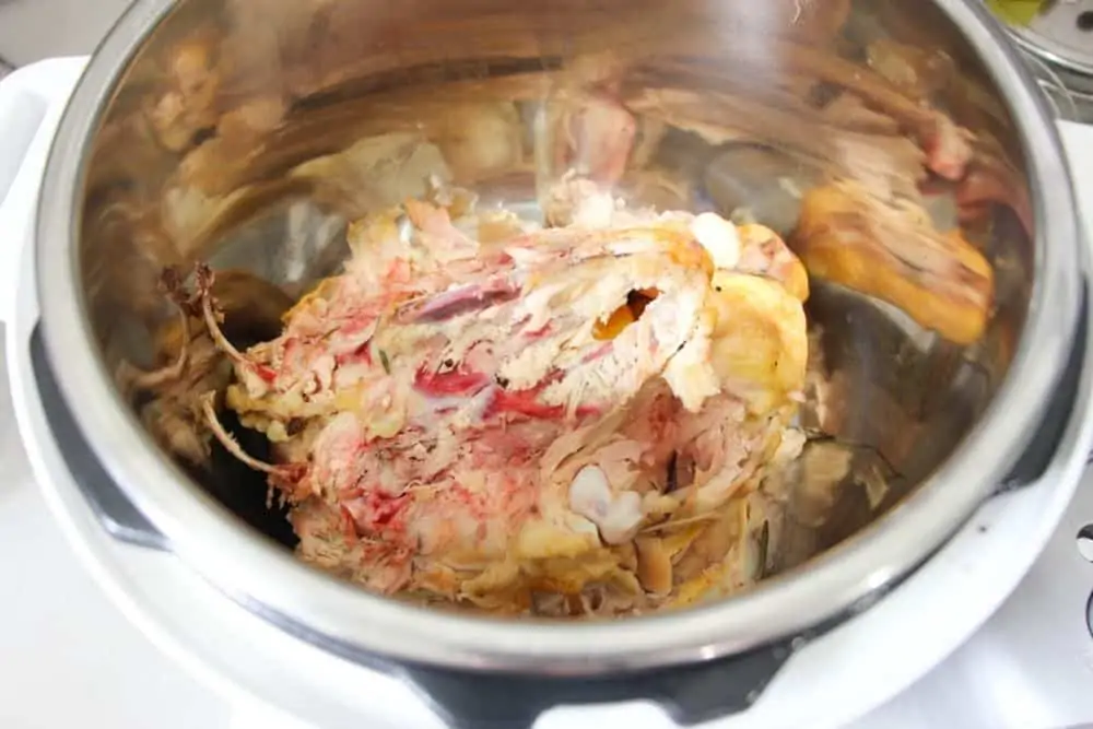 A whole chicken carcass inside of an Instant Pot pressure cooker.