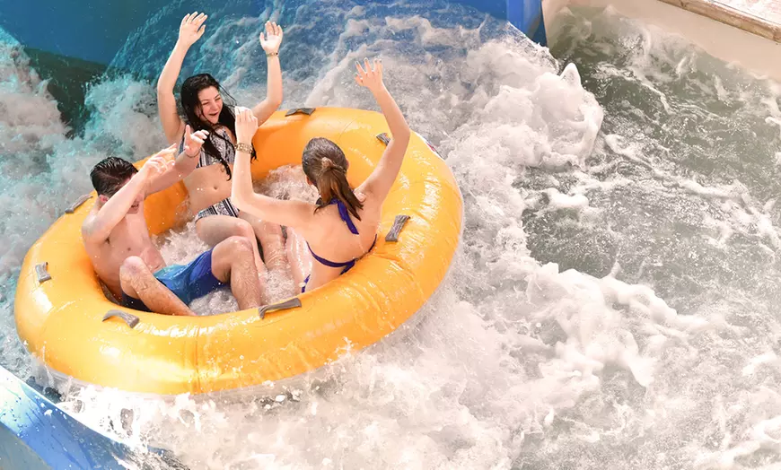Teens riding down a water slide in an innertube. 