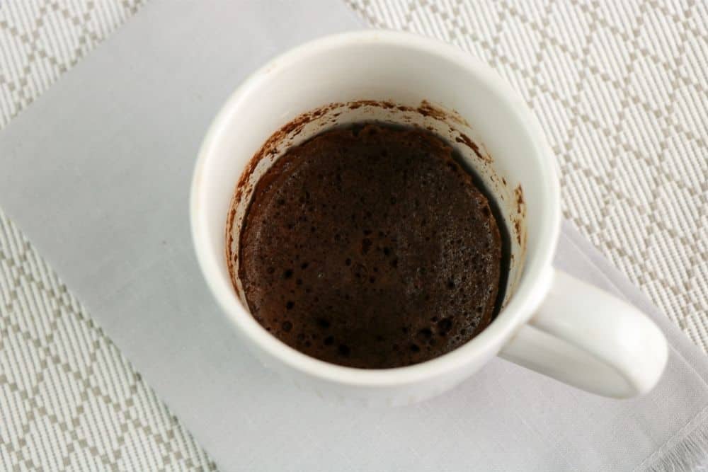 Cooked Chocolate Keto Mug Cake sitting on a gray napkin.