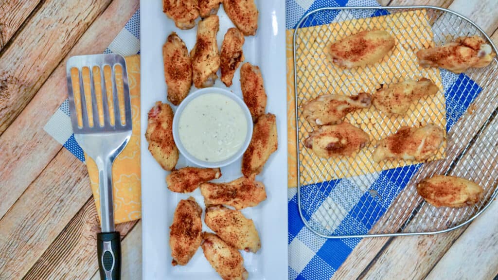 Air Fried chicken wings seasoned with Cajun seasoning blend, sitting on a plate with a bowl of ranch dressing.