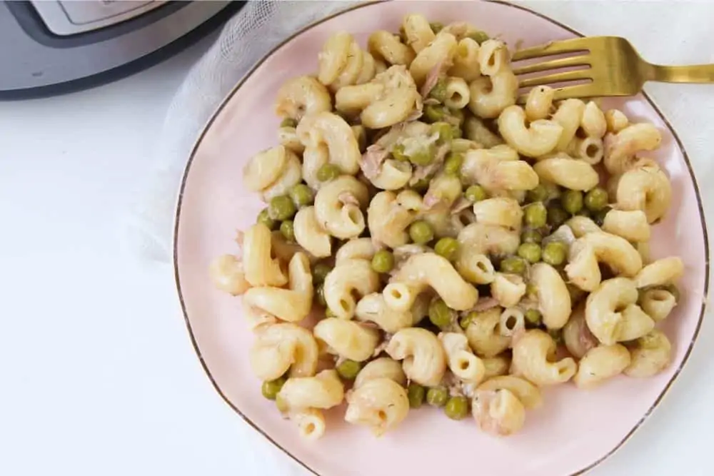 A finished plate full of cooked cheesy tuna noodle casserole with peas.