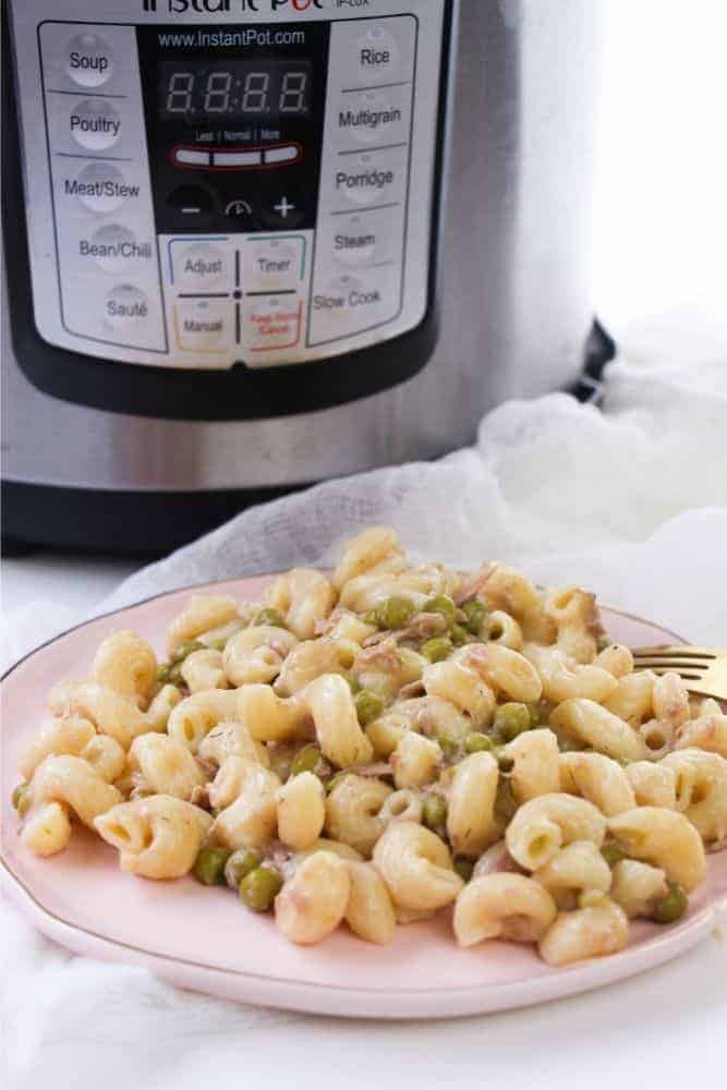 Close up of tuna noodle casserole sitting on a plate in front of an Instant Pot pressure cooker. 