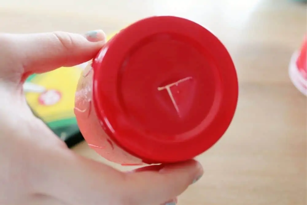 A person showing the bottom of the plastic cup with a slit cut into it. 