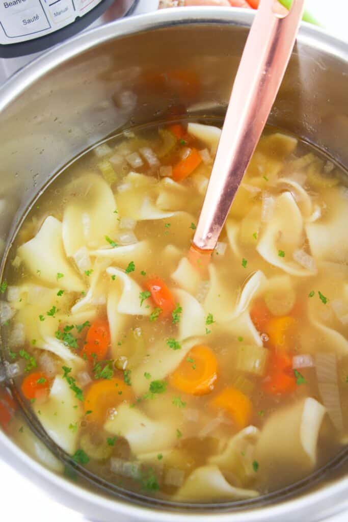 Finished chicken noodle soup in an Instant Pot with a large spoon.