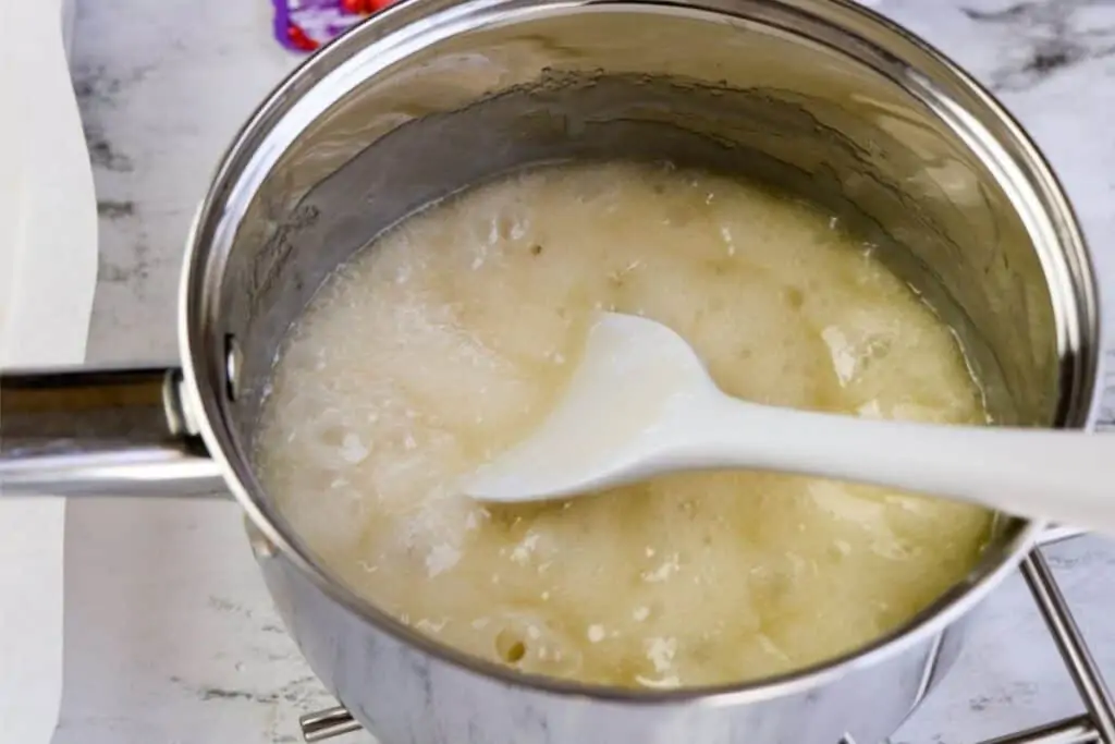 A pot of sugar sauce with a spatula stirring it.