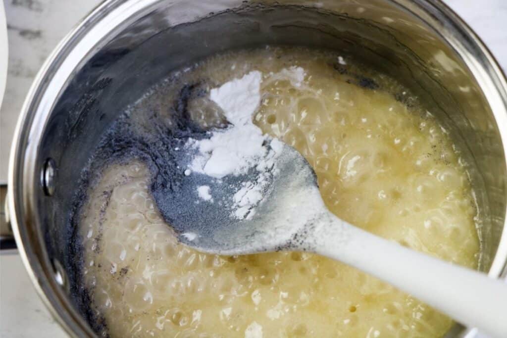 Stirring in powdered drink mix and baking powder to the pot of sugar sauce.
