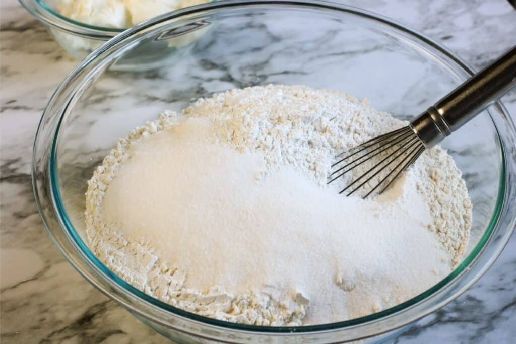 a bowl with all of the dry ingredients to make muffins and a whisk.