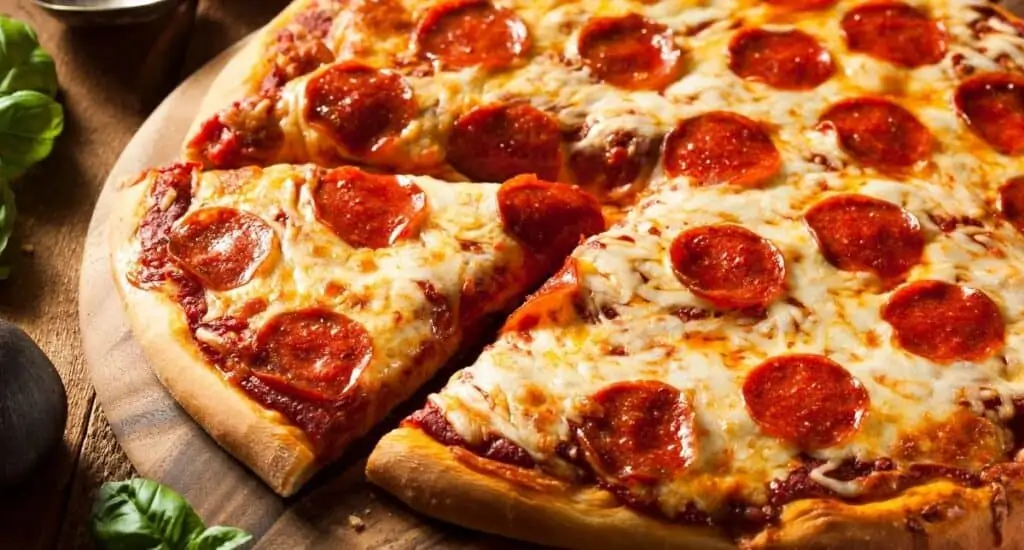 a slice of pizza being taken from a circle pepperoni pizza. 