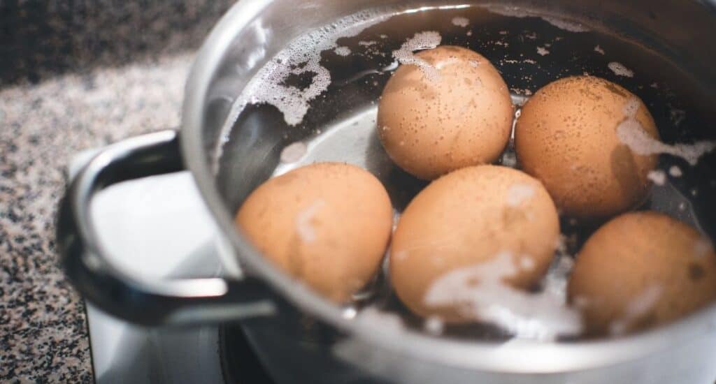 Five fresh farm eggs being boiled in hot water.