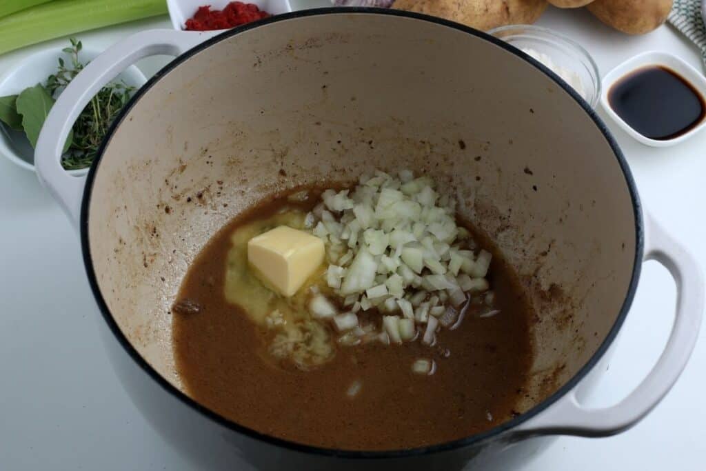 Pot full of butter, broth, and onions.