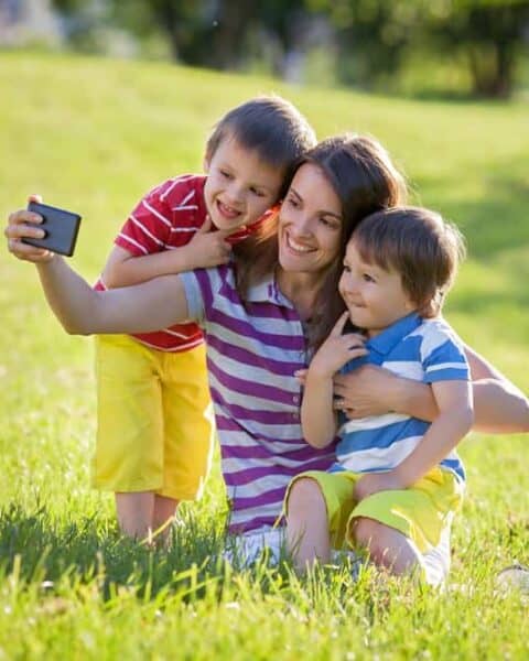 Happy mother with two kids, taking pictures in the park