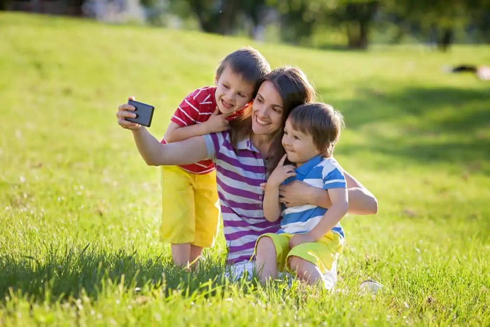 Happy mother with two kids, taking pictures in the park