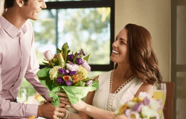 A man handing a woman a bouquet of flowers.