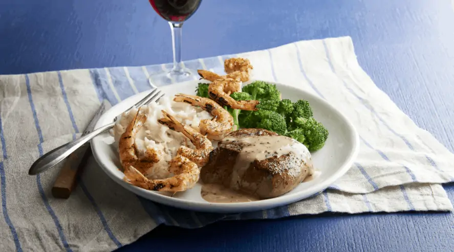 A plate of port, shrimp, and broccoli.