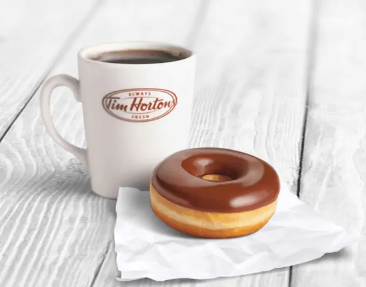 A cup of Tim Horton's coffee and chocolate glazed donut.