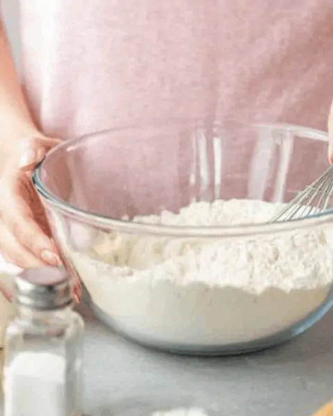 A woman holding a whisk with a mixing bowl of flour and other dry ingredients | Bisquick recipes