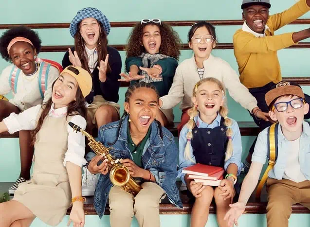 A bunch of happy kids sitting opn school bleachers. 