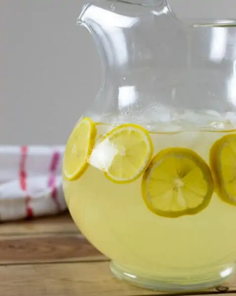 A clear pitcher of lemons and lemonade ready for serving.