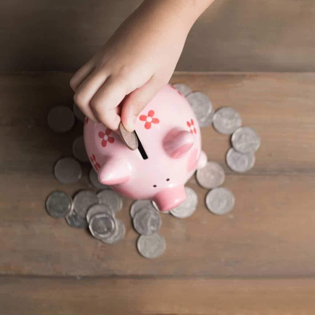 A child placing a quarter in a piggy bank.