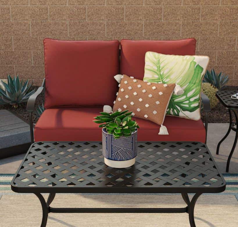 Outdoor furniture with pillows and plants.