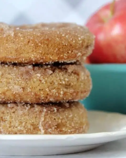 A stack of apple cider donuts on a white plate.