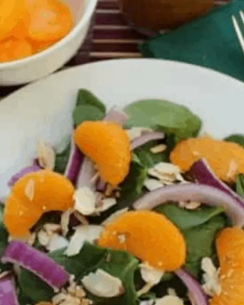Bowl of spinach salad and oranges with red onions.
