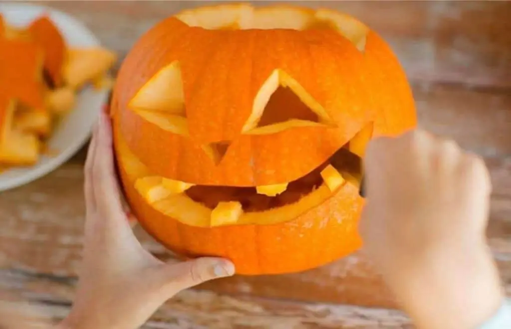 A woman carving a pumpkin's mouth.