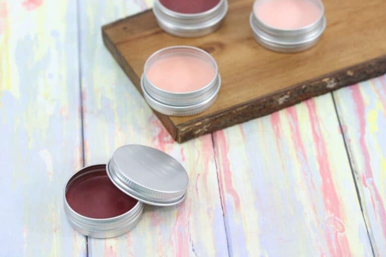 Homemade tinted lip balm on wooden board and table.