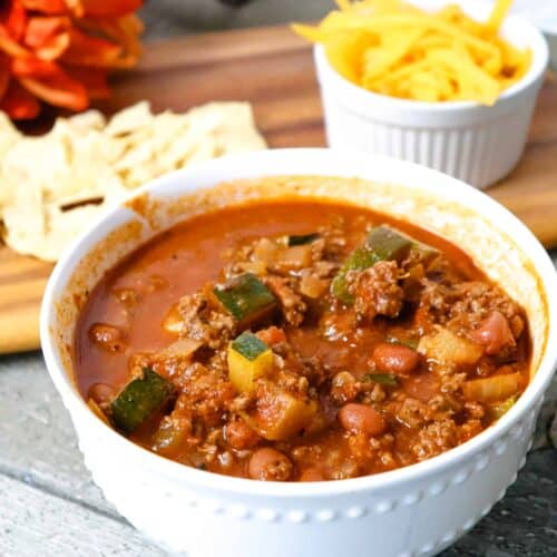 Homemade ground venison chili with shredded cheese and chips.