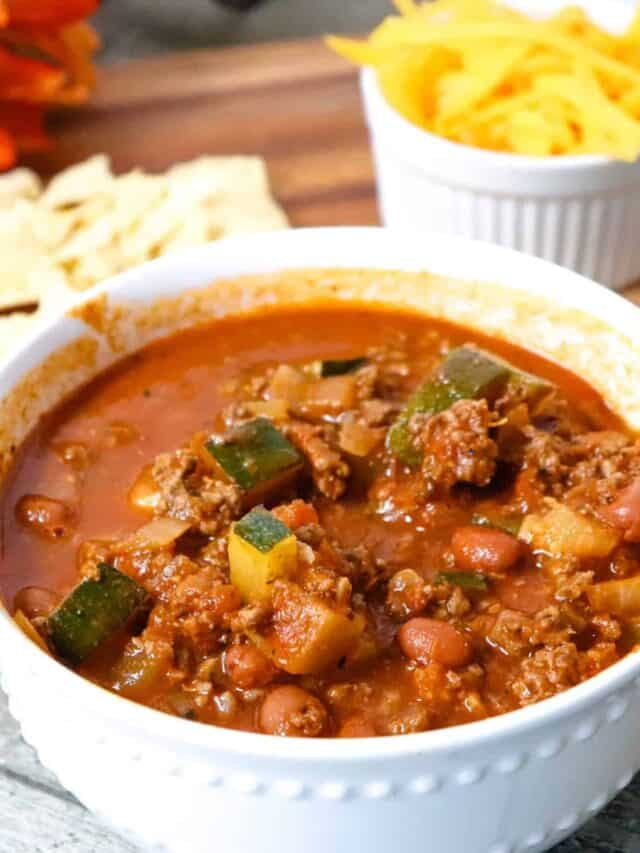 Homemade ground venison chili with shredded cheese and chips.