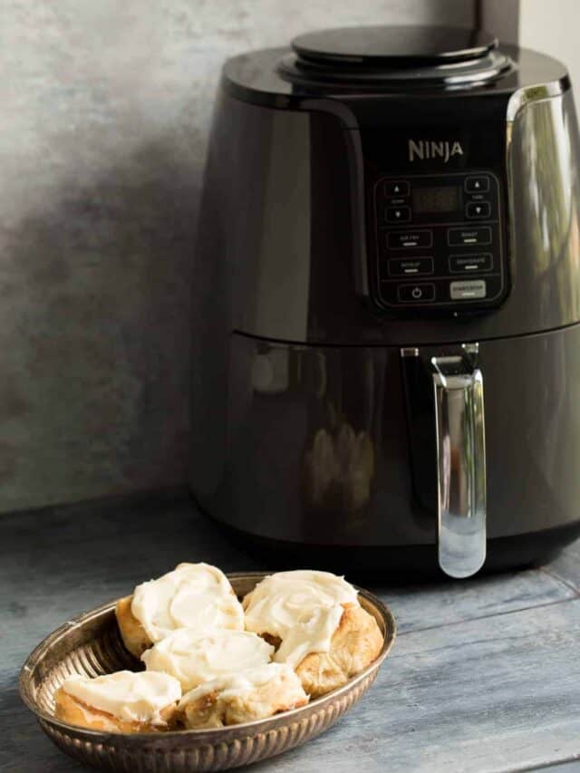 A Ninja airfryer on a kitchen countertop with a basket of cinnamon rolls.