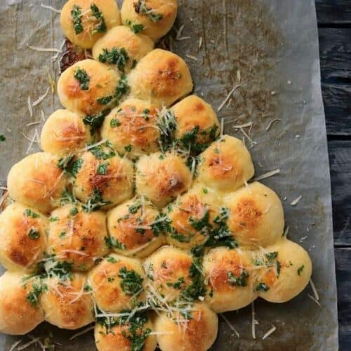 Baked and golden Christmas tree bread with cheese shreds scattered on top.