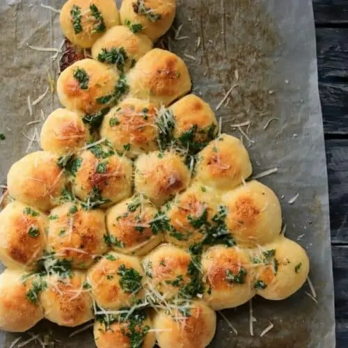 Baked and golden Christmas tree bread with cheese shreds scattered on top.