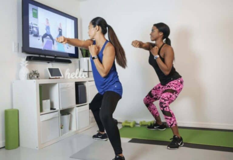 Two women working out together with weights and yoga mat with the Healthy U TV.