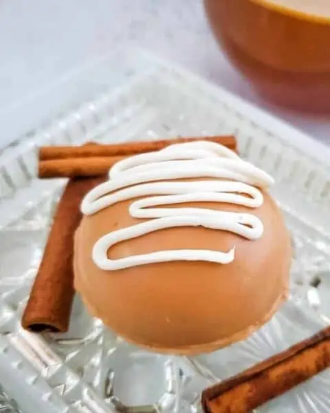 Close up of apple cider bombs on a plate next to cinnamon sticks..