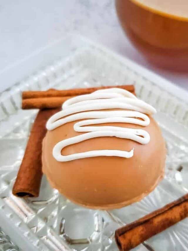 Close up of apple cider bombs on a plate next to cinnamon sticks..