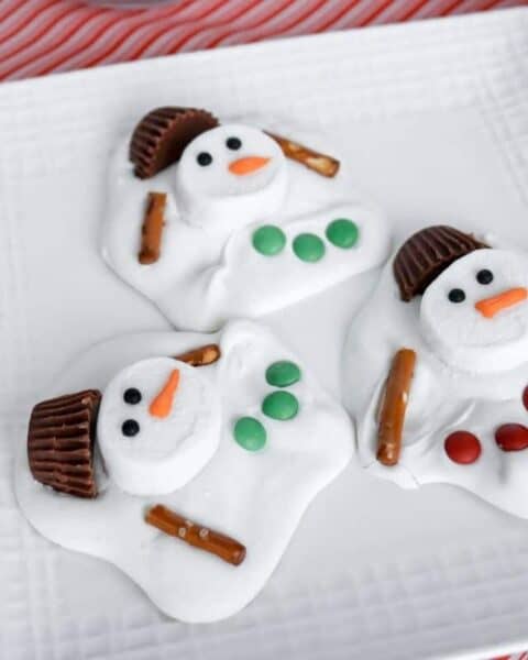 Three melted snowman barks on a white square plate.