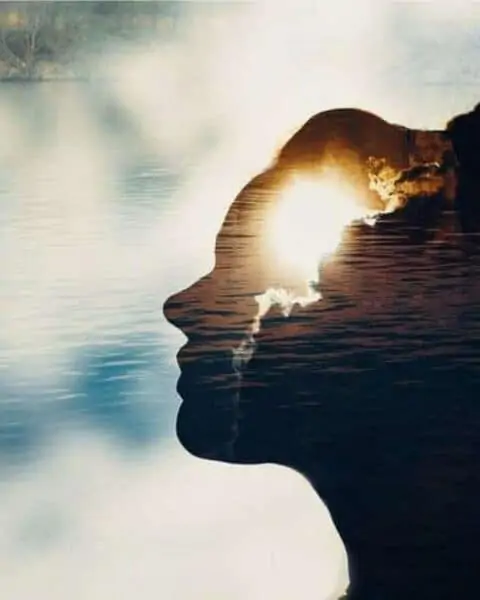 A woman with a silhouette with water against clouds and sunshine.